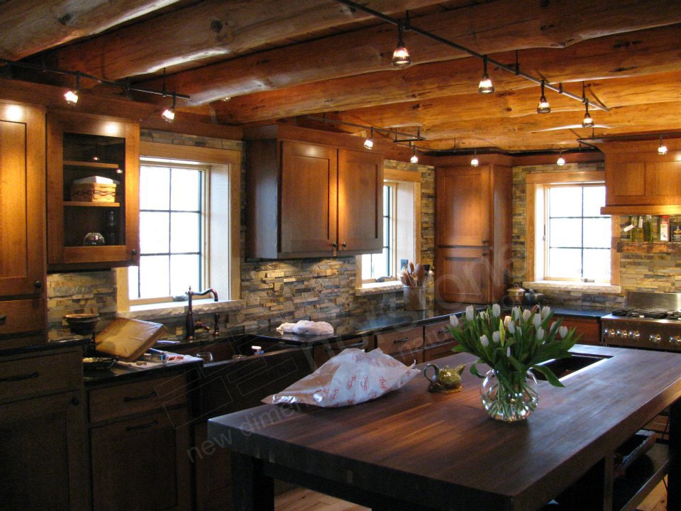 Norstone Ochre Blend Rock Panels on a Rustic Kitchen Backsplash with a large butcher block island and a ceiling with exposed natural log beams